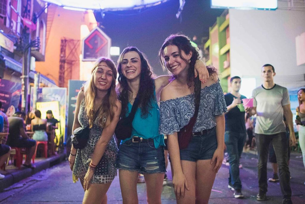 Three travellers on Khaosan Road in Bangkok at night.